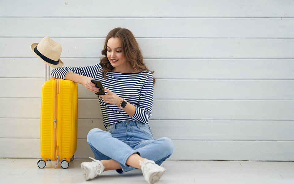 Super Last Minute: Frau mit Koffer und Smartphone