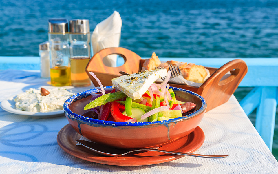 Typisch griechischer Salat mit Feta, frischem Gemüse und Olivenöl, serviert in einer Taverne mit traumhaftem Meerblick